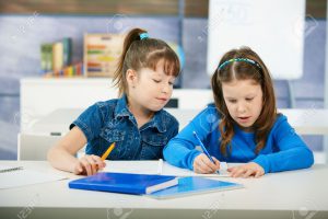 Children sitting at desk and learning together in primary school classroom Elementary age children.
